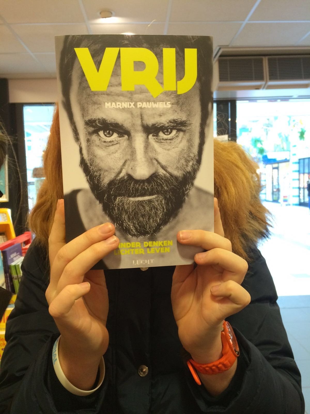 Een lezer houdt het boek Vrij van Marnix Pauwels voor haar gezicht